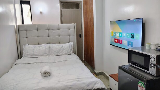 Ein Schlafzimmer mit einem Bett, einem an der Wand montierten Fernseher und einer Mikrowelle auf einem Schrank.