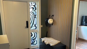 Ein Zimmer mit einer Schiebetür, einem schwarzen Stauraum, einem Deckenventilator und Holzboden.