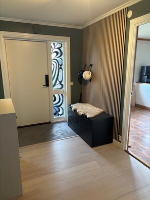 Ein Zimmer mit einer Schiebetür, einem schwarzen Stauraum, einem Deckenventilator und Holzboden.