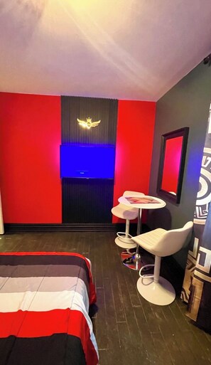 A hotel room with a bed, a small table with a chair, a television, and a wall with a decorative emblem. - Luxury KIA Room D
Private master 
In Richmond hill (Richmond Hill)
