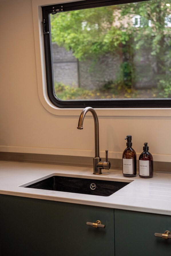 A kitchen with a window, a sink, and two hand wash bottles.