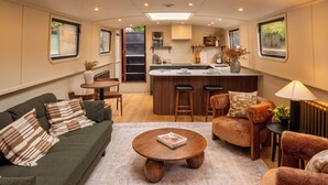A compact living space with a kitchenette, a sofa, a coffee table, and a dining area. - Gainsborough Boat House (London)