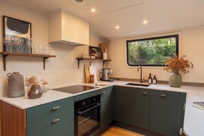 A modern kitchen with a built-in oven, a window, and a countertop with various items.
