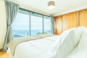 Ein Schlafzimmer mit einem großen Bett, Meerblick und einer Wand aus Holzpaneelen.