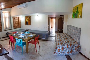 Ein Zimmer mit Esstisch für vier Personen, einer Couch, einem Bett und einer Ziegelwand.