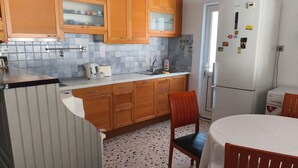 Une cuisine de taille réduite, dotée de meubles en bois, d’un réfrigérateur blanc, d’un évier et d’une table à manger avec des chaises.