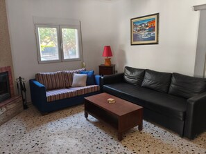 Un salon avec une cheminée, deux canapés, une table basse, une lampe et un tableau encadré.