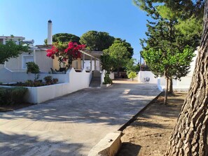 A residential street with houses, a clear sky, and trees. - Holiday Home 'Nicks House By Zarkco' with Private Terrace, Wi-Fi and Air Conditioning (Artemida)