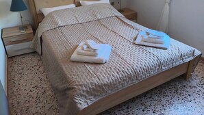 Un lit bien fait, recouvert d’une couverture à motifs, avec deux lampes de chevet et une fenêtre agrémentée d’un rideau.