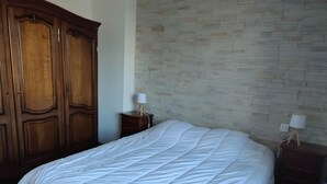 A bedroom with a large bed, wooden wardrobe, and two bedside tables with lamps. - Holiday Home “Gîte for 10 in Barfleur” with Private Terrace, Garden & Wi-Fi (Barfleur)