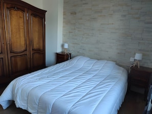 Ein Schlafzimmer mit einem großen Bett, einem Holzschrank und zwei Nachttischen mit Lampen.