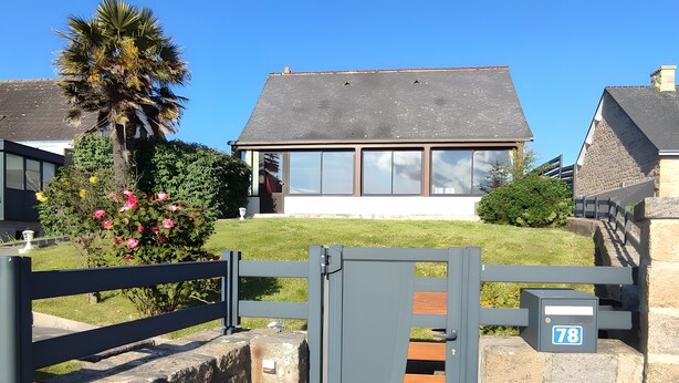 A gated entrance with a stone wall, a house with a grey roof, and a clear blue sky. - Holiday Home “Gîte for 10 in Barfleur” with Private Terrace, Garden & Wi-Fi (Barfleur)