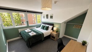 A bedroom with a bed, bedside table, lamp, chair, and a view of the outside. - 6-bed House - Sleeps 11 - Garden - Parking (Sheffield)