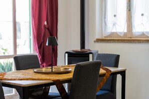 Ein Essbereich mit Tisch, Stühlen, einer Lampe und einem Fenster mit Vorhängen.