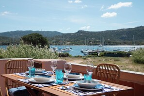 A table set for dining with a view of boats and hills. - Nuraghi 42 by Wonderful Italy (Cannigione)