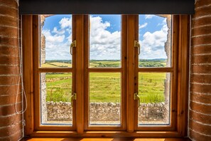 Ein Fenster mit Blick auf eine ländliche Landschaft, Holzrahmen und Steinmauer.
