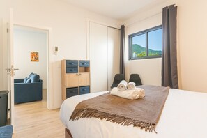 Une chambre d’hôtel comprenant un lit, un bureau avec des tiroirs, une chaise, un canapé et une fenêtre donnant sur une vue sur la montagne.