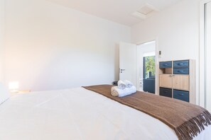 Ein Hotelzimmer mit einem Bett, einer Nachttischlampe, einem Holzschrank und einer Tür zum Balkon.