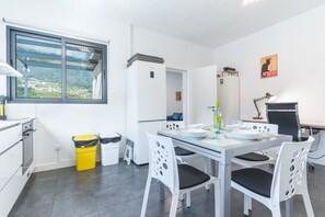 Eine moderne Küche mit Essbereich, einem Fenster und Blick sowie einem Mülleimer.