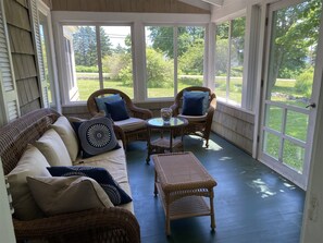 A covered porch with wicker furniture, including a sofa and chairs, and a small table. - DRIFT INN COTTAGE-1 mile from Port Clyde & Walk to Drift Inn Beach, Dog-Friendly (St. George)