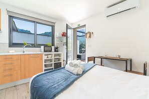 Ein modernes Hotelzimmer mit Bett, einer Küchenzeile, einem Badezimmer und Blick auf die Berge.
