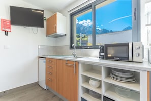 Eine Küche mit Holzausstattung, einer Mikrowelle, einem Spülbecken und einem Fenster mit Blick auf die Berge.