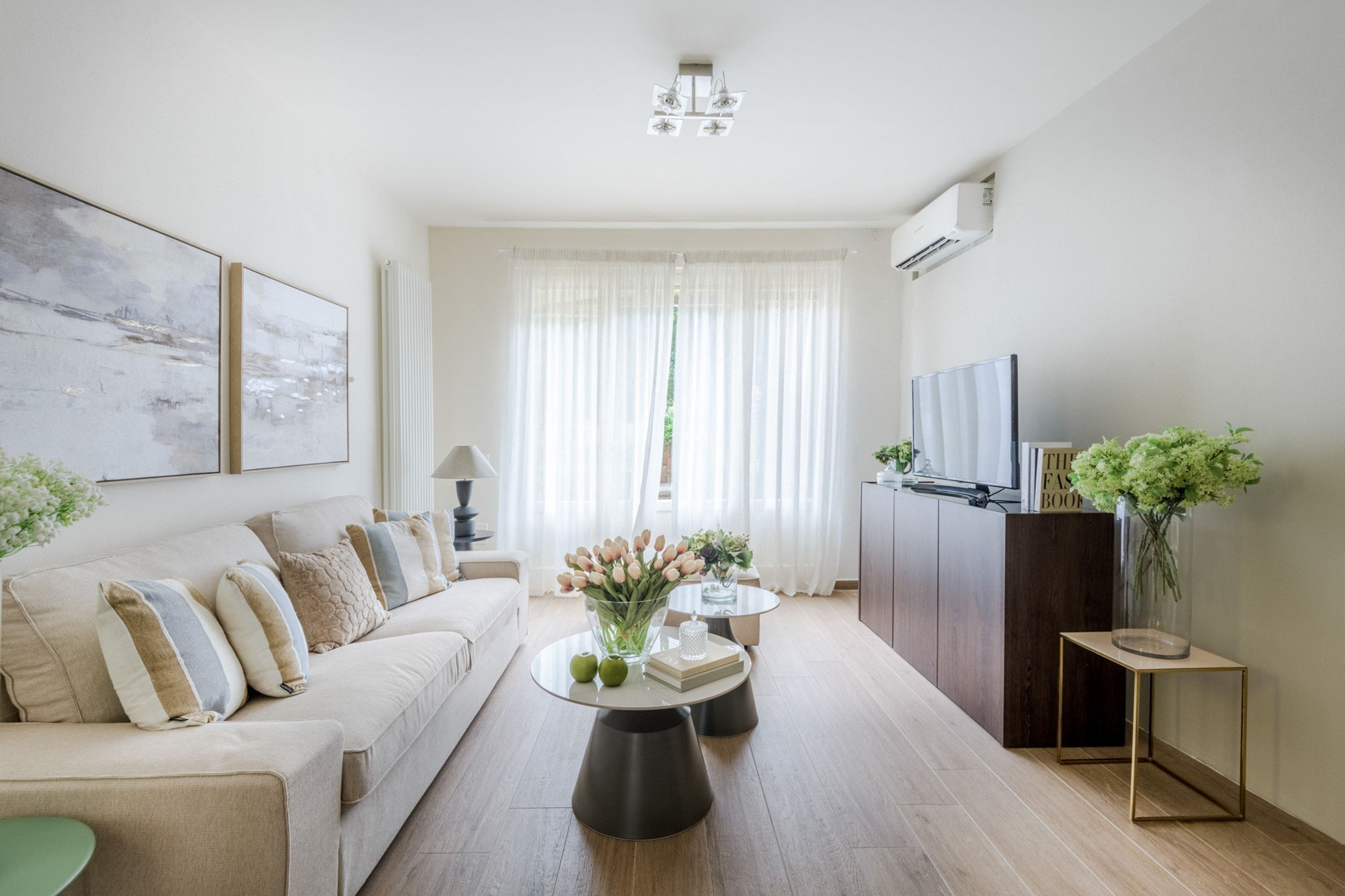 Un salon moderne avec un canapé, une table basse, un téléviseur et des plantes décoratives.