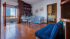 A living room with a dining area, a sofa, a bookshelf, and a balcony. - GuestHost - La Pavoncella Terrace Apartment (Cagliari)
