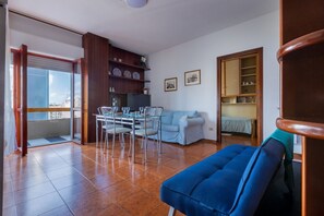 A living room with a dining area, a sofa, a bookshelf, and a balcony. - GuestHost - La Pavoncella Terrace Apartment (Cagliari)