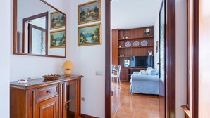 A hallway with a wooden cabinet, a mirror, and two framed paintings. - GuestHost - La Pavoncella Terrace Apartment (Cagliari)