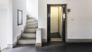 A staircase leading to an elevator, a framed picture on the wall, and a no-smoking sign. - GuestHost - La Pavoncella Terrace Apartment (Cagliari)