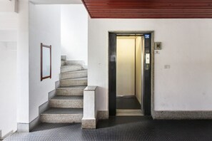 A staircase leading to an elevator, a framed picture on the wall, and a no-smoking sign. - GuestHost - La Pavoncella Terrace Apartment (Cagliari)