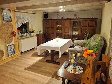 A cozy room with a wooden table, a cushioned chair, a radiator, and a cabinet with glass doors.. Haus Semmelrodt small vacation home between the castles Ludwigstein and Hanstein