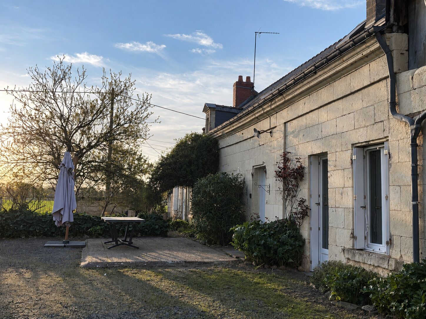 A stone building with a garden, a table, and a chair.