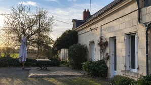 Un bâtiment en pierre avec un jardin, une table et une chaise.