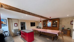 Une cuisine avec un îlot central rouge, des meubles de rangement en bois et une table à manger.