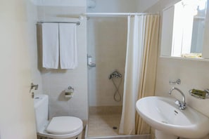 A bathroom with a toilet, a shower with a curtain, and a sink.