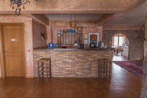 A kitchen with a brick counter, wooden stools, and a door with a sign.