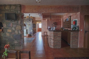 A spacious living area with a stone wall, a brick fireplace, and a kitchen area with a bar.