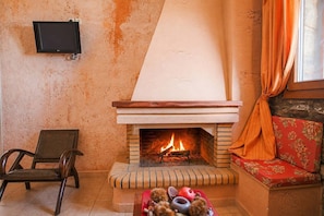 A cozy living room with a fireplace, a television mounted on the wall, a sofa, and a chair.