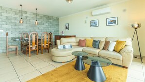 A living room with a sofa, coffee table, dining table, chairs, and pendant lights. - Villa Saudade by Atlantic Holiday (Ponta do Sol)