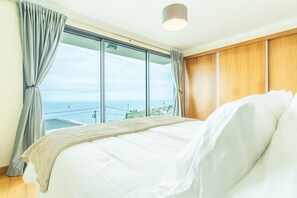 Ein Schlafzimmer mit einem großen Bett, Meerblick und einer Wand aus Holzpaneelen.