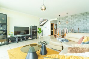 Ein modernes Wohnzimmer mit Sofa, Fernseher und einer Treppe, die zu einer weiteren Ebene führt.
