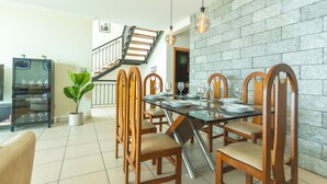 A dining area with a glass table, wooden chairs, a staircase, and a stone wall. - Villa Saudade by Atlantic Holiday (Ponta do Sol)