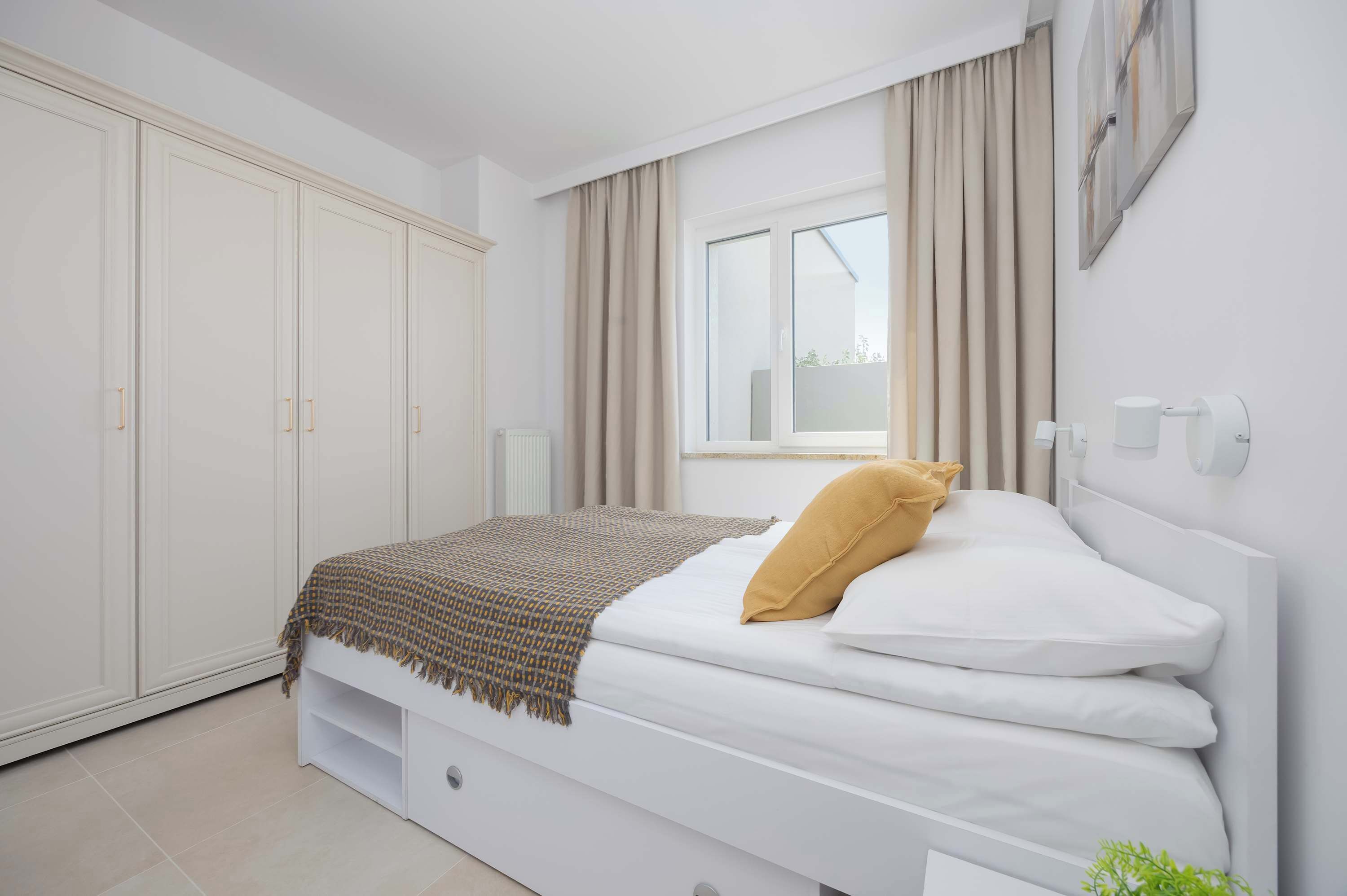 A bedroom with a bed, a wardrobe, a window, and a radiator.