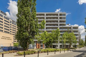 A multi-story building with a modern design, surrounded by trees and a clear sky. - Family Apartment with Terrace | 2 Bedrooms | Balcony (Warszawa)