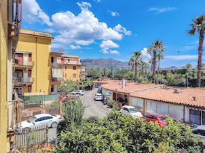 Una calle residencial con coches aparcados, edificios amarillos y palmeras.