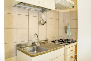 A kitchen with a sink, stove, and overhead ventilation. - Loving Gift (Giardini Naxos)