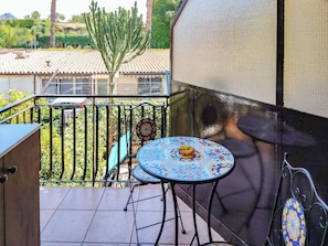 A balcony with a tiled floor, a table with a decorative top, a chair, and a large cactus in the background. - Loving Gift (Giardini Naxos)