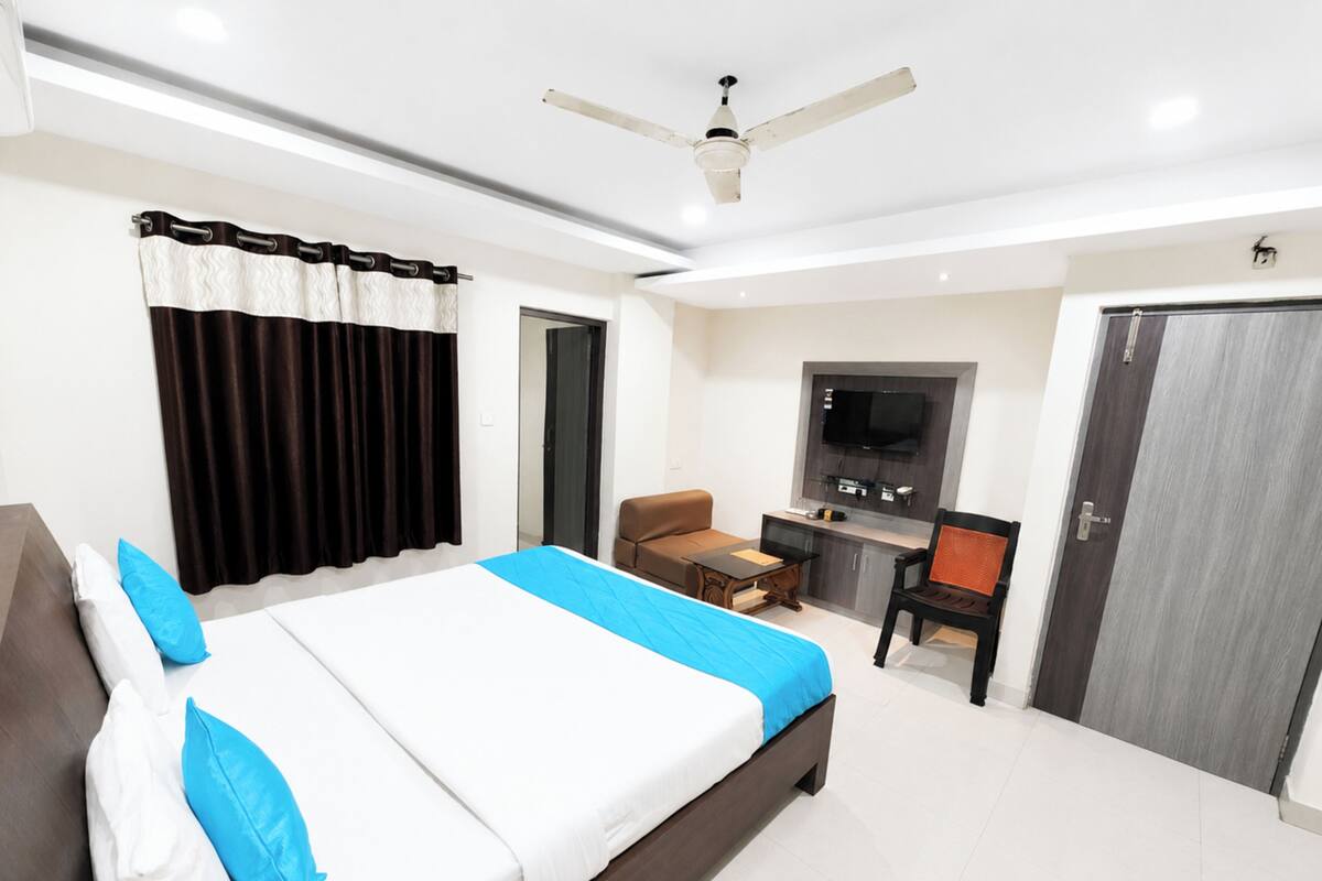A hotel room with a bed, a desk, a chair, a TV, and a wardrobe.